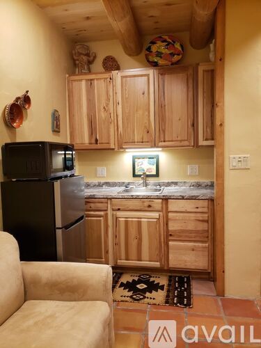 A kitchen with wooden cabinets and a black fridge.