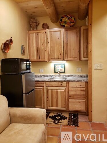 A kitchen with wooden cabinets and a black fridge.