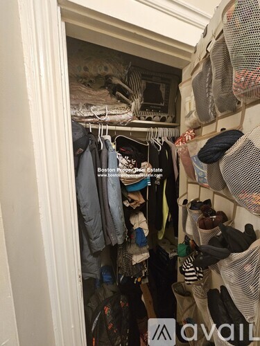 A small closet with clothes hanging on a wire rack.