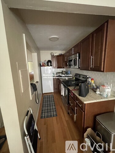 A kitchen with wooden cabinets and a checkered mat on the floor.