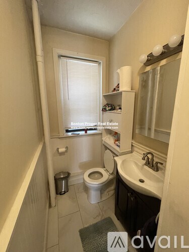 A bathroom with a toilet, sink, and mirror.