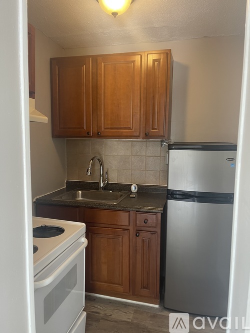 A kitchen with wooden cabinets and a stainless steel refrigerator.