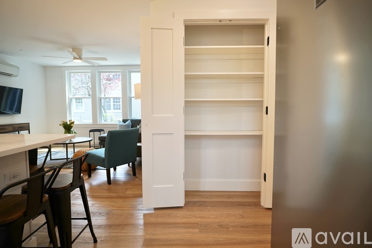 A kitchen with a dining table and chairs is visible through an open door.