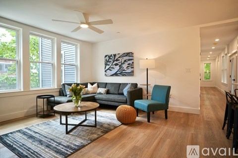 A living room with a grey sofa, a green chair, a coffee table, and a painting on the wall.