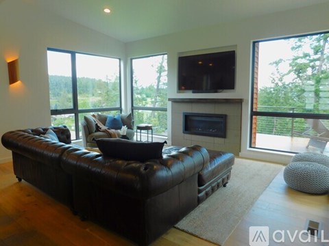 A living room with a black leather couch and a fireplace.