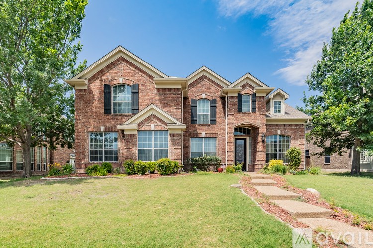 A large brick house with a front yard and a clear blue sky.
