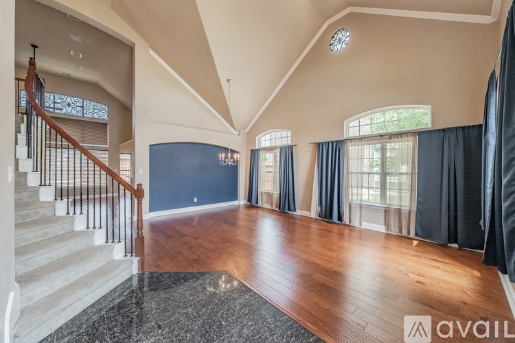 A spacious living room with a staircase on the left and a large window on the right.