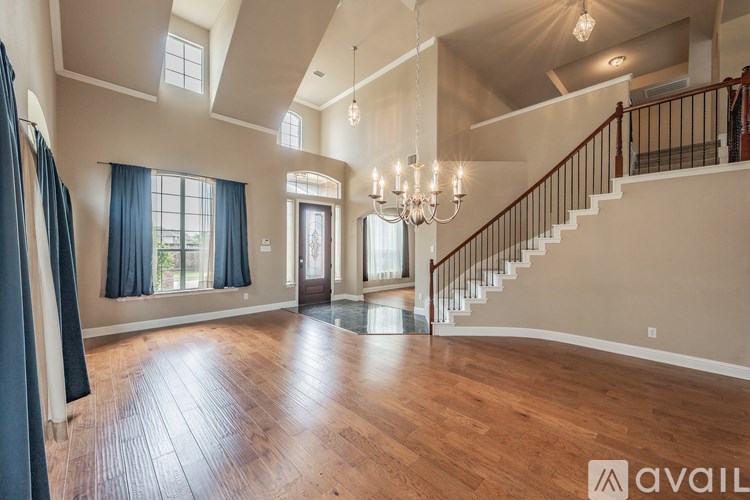 A spacious room with wooden floors and a staircase leading to the upper level.
