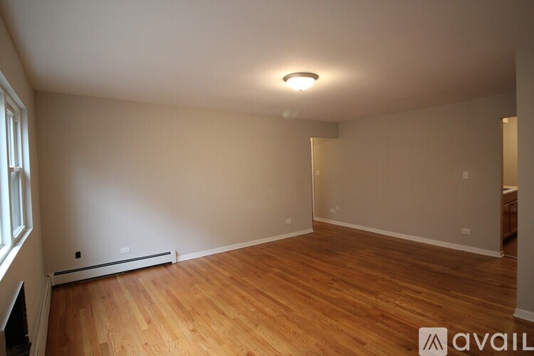 A room with wooden flooring and a window on the left side.