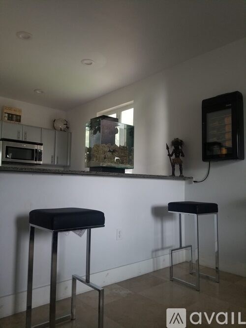 Two black stools are in front of a white wall.