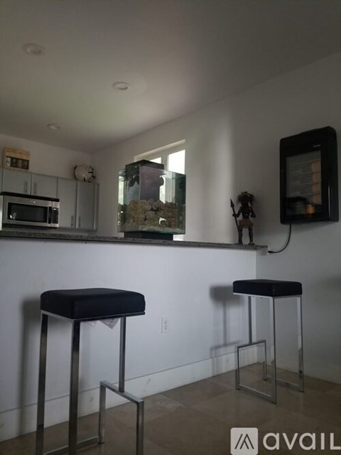 Two black stools are in front of a white wall.