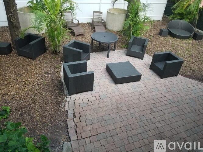 A set of black outdoor furniture is arranged on a brick patio.