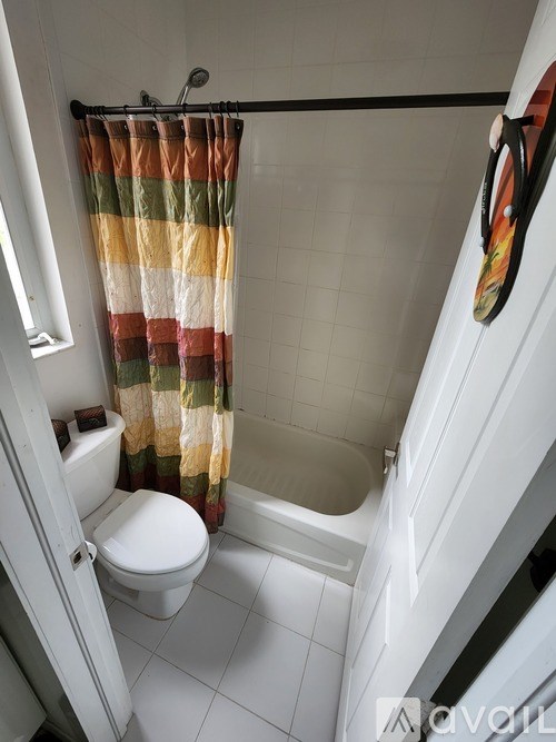 A white toilet with a striped shower curtain in a bathroom.