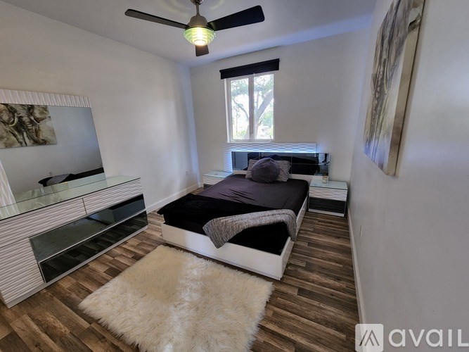 A bedroom with a bed, dresser, and a ceiling fan.