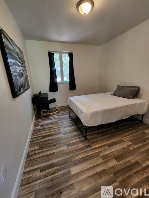 A bedroom with a bed, nightstand, and a painting on the wall.