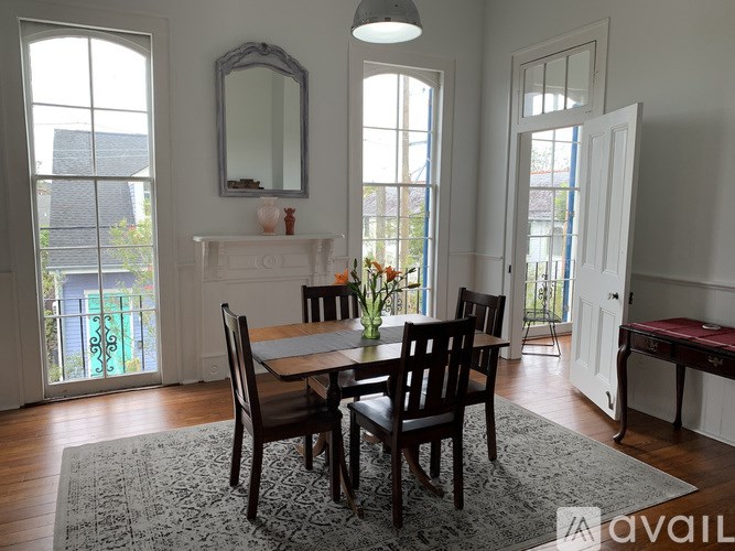 A dining room with a table set for two and a view of a garden through the windows.