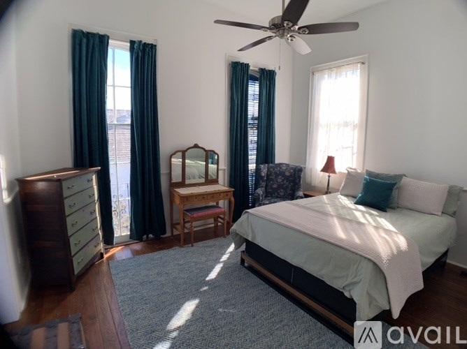 A bedroom with a bed, dresser, and window with curtains.