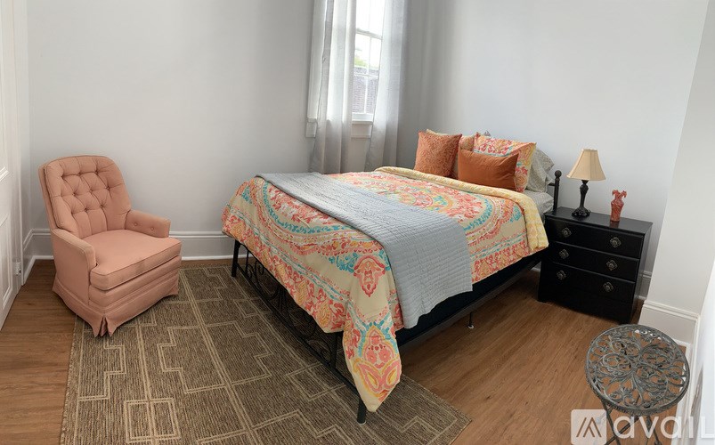 A bedroom with a bed, chair, and lamp.