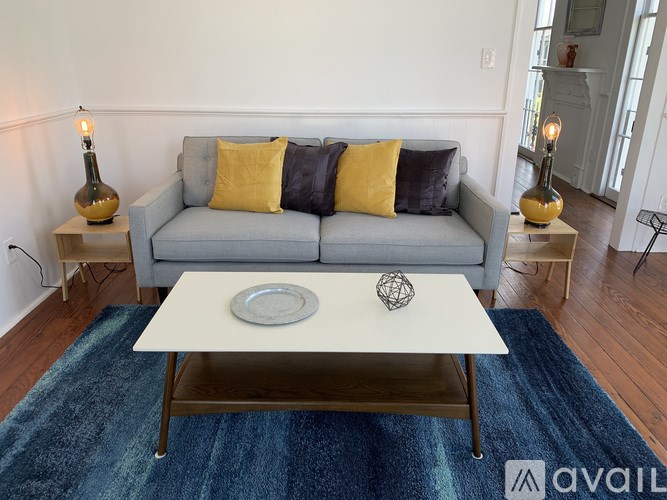 A living room with a grey couch, a white coffee table, and a blue rug.