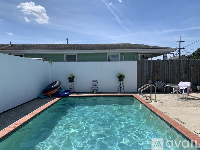 A pool in a backyard with a white chair and a white towel on a chair.
