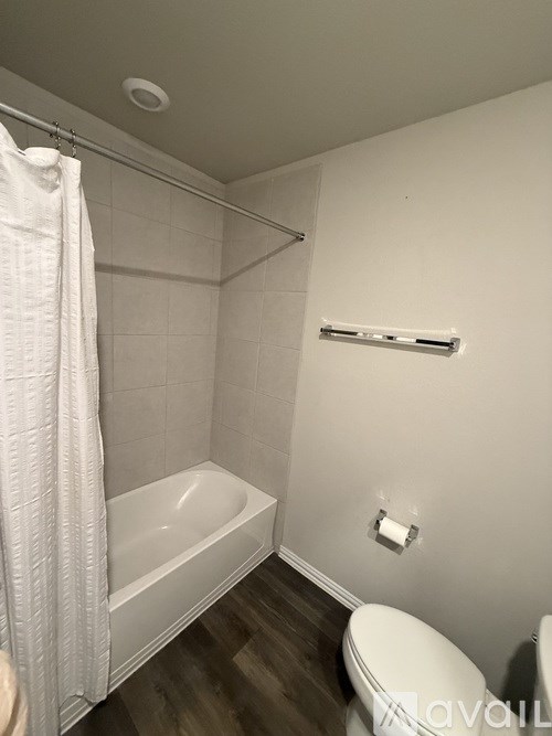 A shower area with a glass door and a glass shelf with toiletries on it.