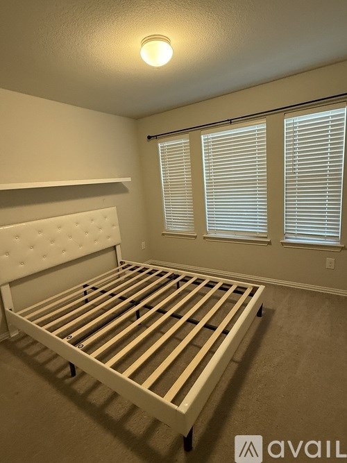 A bedroom with a bed, a ceiling fan, and a window with blinds.