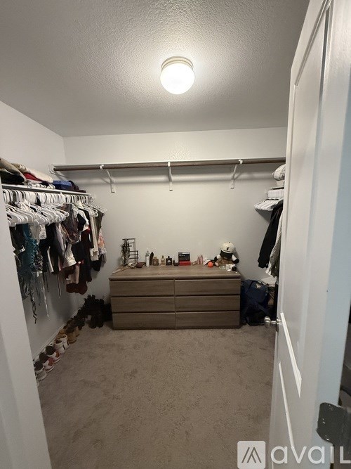 A small, untidy bedroom with a bed and a closet full of clothes.