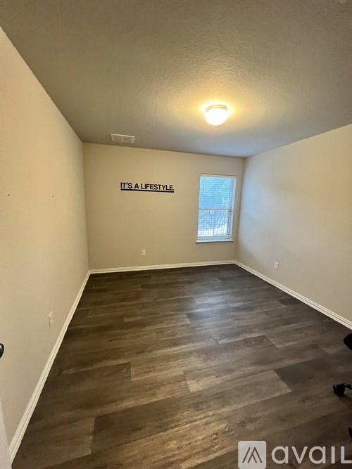 A room with wooden flooring and a window with blinds.