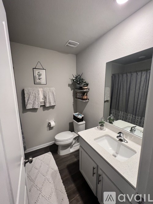 A bathroom with a toilet, sink, and mirror.