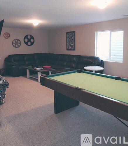 A pool table in a room with a couch and a chair.