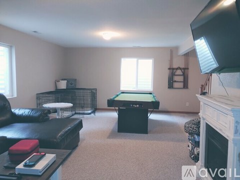 A living room with a pool table and a fireplace.