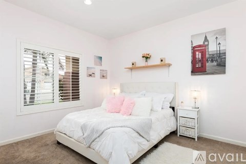 A bedroom with a large bed, a window with blinds, and a red telephone booth poster on the wall.