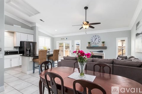 A kitchen with a dining table set up with chairs and a vase of flowers.