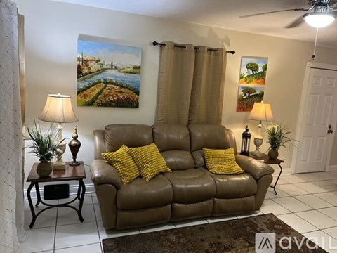 A living room with a brown leather couch and two lamps.