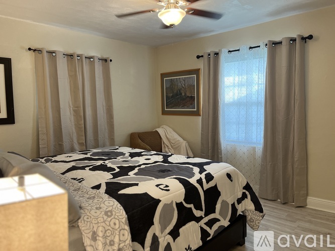 A bedroom with a bed covered in a black and white cow print comforter.