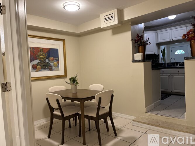A dining room with a table and chairs and a painting on the wall.