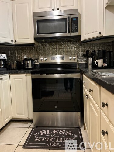 A kitchen with a black stove top oven and a black and white mat on the floor.