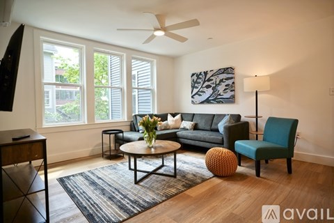 A living room with a grey couch, a green chair, a coffee table, and a painting on the wall.