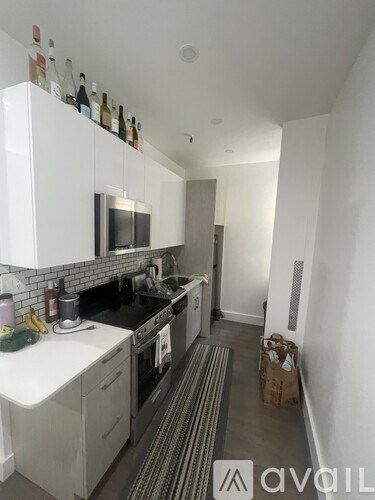 A kitchen with white cabinets and black countertops.
