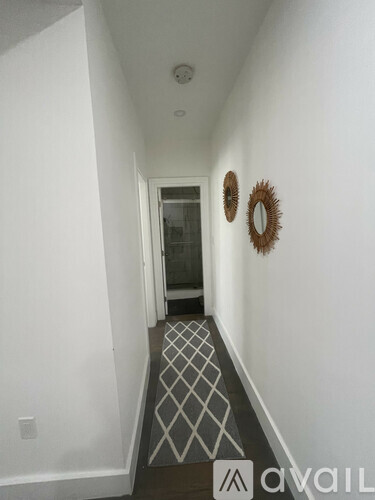 A hallway with a diamond patterned floor and two round mirrors on the wall.