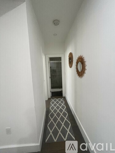 A hallway with a diamond patterned floor and two round mirrors on the wall.