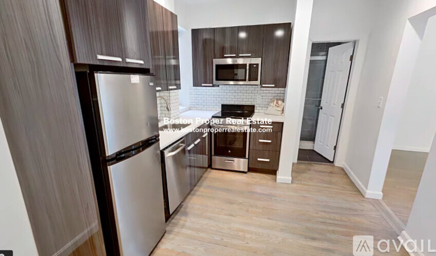A kitchen with a refrigerator, microwave, and oven.