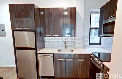 A kitchen with wooden cabinets and a stainless steel refrigerator.