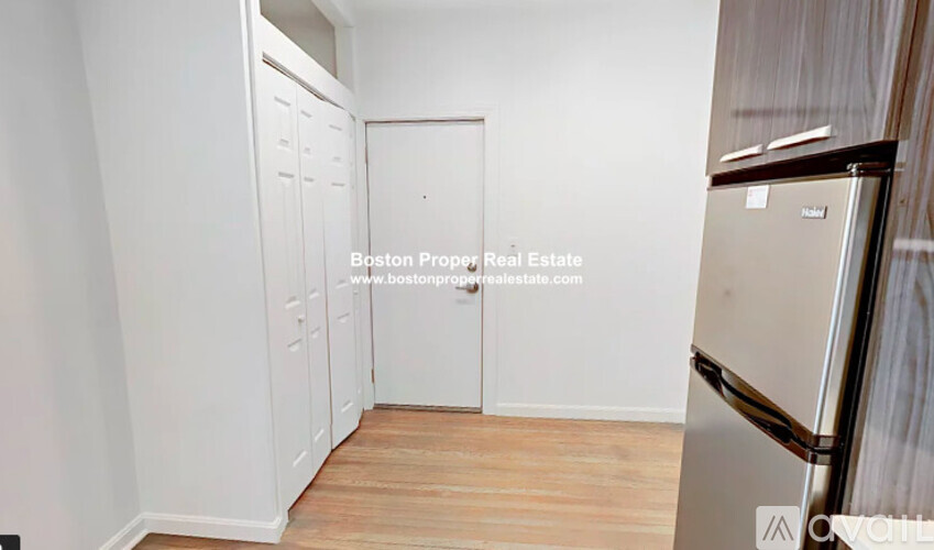 A white door in a room with a fridge on the right.