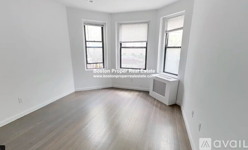 A room with wooden flooring and two windows is available for rent.