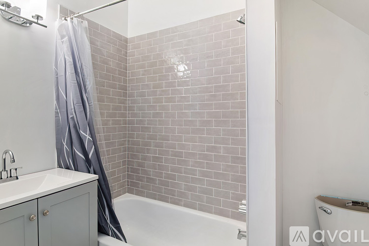 A bathroom with a white sink and a shower with a grey curtain.