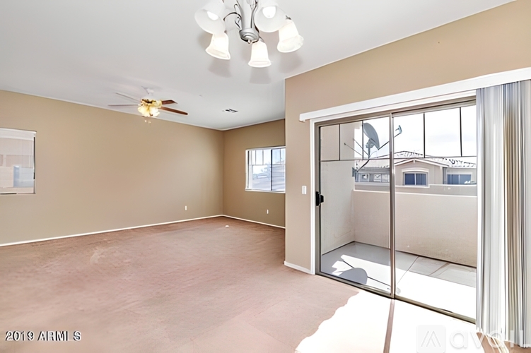 A room with a ceiling fan and sliding glass doors.