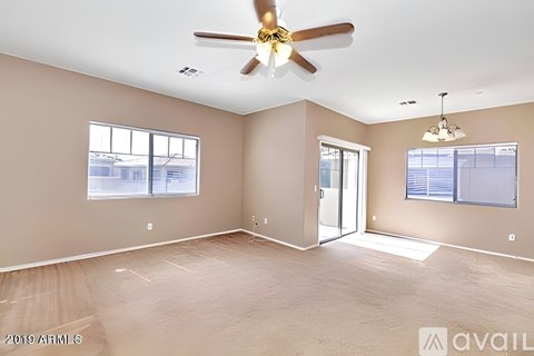 A spacious room with a ceiling fan and sliding glass doors.