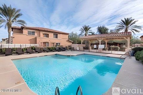 A large swimming pool in front of a building with a covered patio area.
