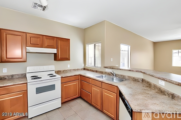 A kitchen with a white stove top oven and brown cabinets.